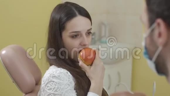 戴牙椅的美女画像女孩吃苹果看着相机的概念视频的预览图