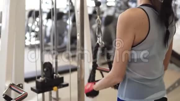 运动员在健身房的机器上做三头肌的练习穿运动服的女孩训练视频的预览图