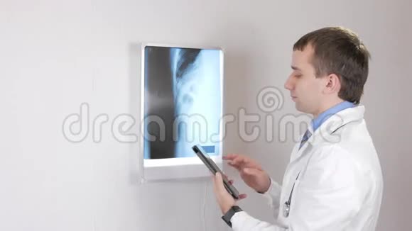 一个年轻的医生一个男人在平板电脑上记录x射线数据带有肋骨和肋骨的X光透视器视频的预览图