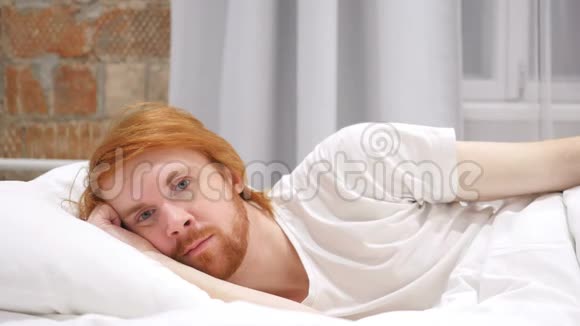 躺在床上的年轻红发胡子男的脸视频的预览图