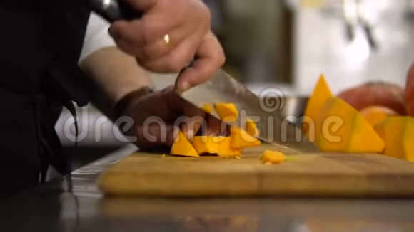 厨师把厨房里的一个大南瓜切成小块特写用来煮汤视频的预览图