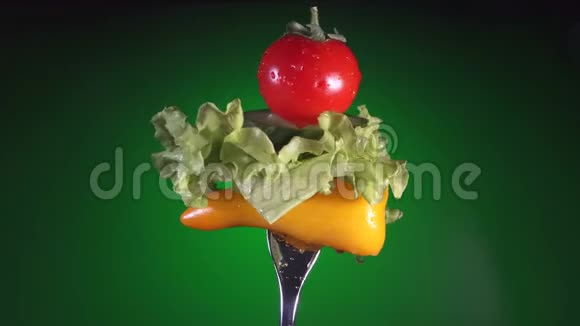 用黄椒片叉黄瓜萝卜和生菜旋转绿色背景视频的预览图