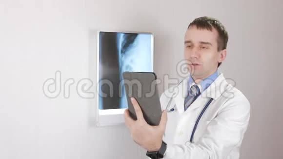 医生用平板电脑在互联网上和pachinte说话白色墙壁和X光观看者肋骨和肋骨视频的预览图