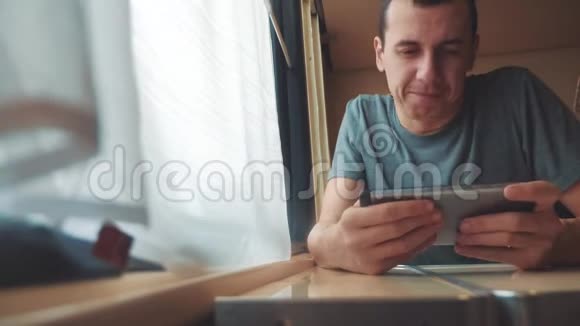 男人在智能手机上玩网络游戏强烈的情绪愤怒的男人坐在窗边的火车上慢动作视频的预览图