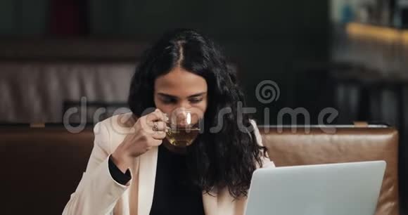 商务女性坐在咖啡馆里拿着笔记本电脑吃晚饭桌上放着一杯茶上班吃午饭视频的预览图
