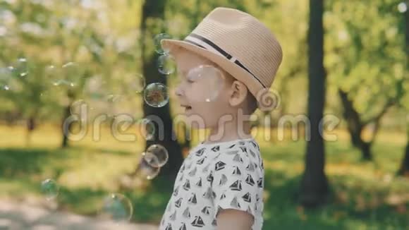 戴帽子的小男孩捕捉泡泡小孩子在外面玩父母视频的预览图