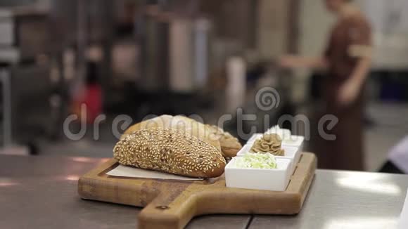 在一个木制托盘上放着芝麻面包和带有调味品的盘子视频的预览图