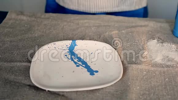 巫师把蓝色的油漆溅在白色的盘子上在桌子上打嗝创意工作坊视频的预览图