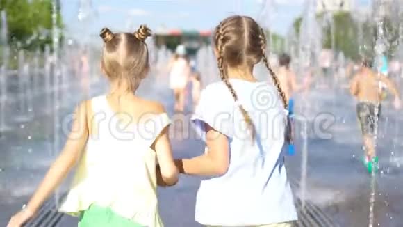 在炎热的阳光明媚的日子里小可爱的女孩在街头喷泉里玩得很开心视频的预览图