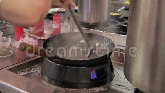 厨师在炉子上准备食物在现代化的大型餐厅厨房里用火煎锅视频的预览图