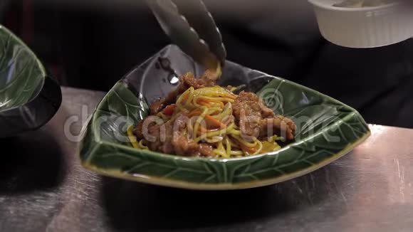 厨师们把蘑菇放在一个乌冬面上在一个绿色的亚洲盘子里放着炒肉视频的预览图