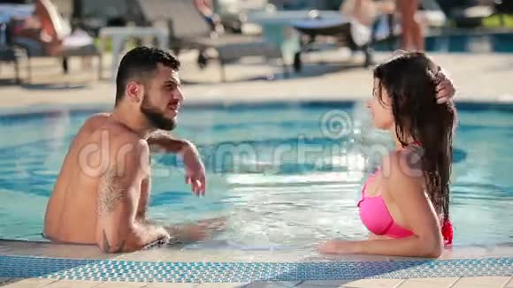 一个长着胡子的野蛮男人在游泳池里和漂亮的黑发女人说话视频的预览图