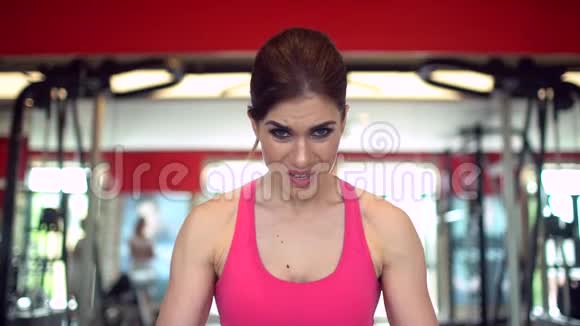 肌肉发达的女运动员穿着粉红色上衣在健身房锻炼举重健身女孩在健身房锻炼这就是视频的预览图