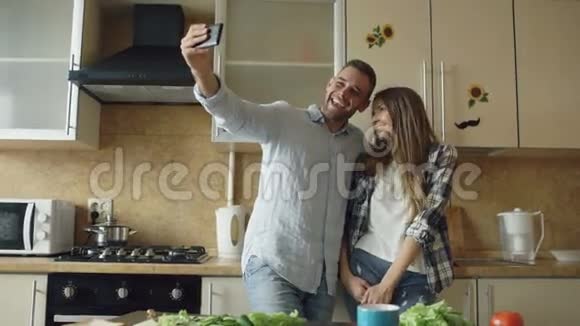 年轻的幸福夫妇在家里的厨房里做早餐时自拍视频的预览图