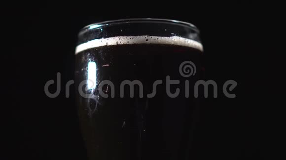 一品脱黑啤酒在黑色背景下旋转结实的玻璃在旋转视频的预览图