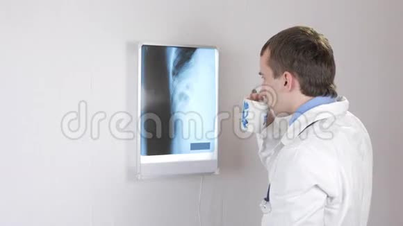 医生检查X光喝一杯热饮料有肋骨和胸部的白壁和黑镜视频的预览图