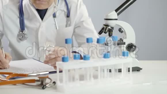 男医生拿着药罐用银笔在工作台上开处方视频的预览图