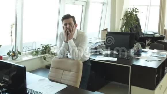 一位年轻的商人在办公室为一位朋友欢呼视频的预览图