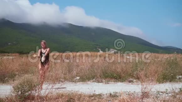 阳光明媚的日子里性感的女孩在山里的路上跳舞那个金发女孩穿着开放式泳衣跳舞很有趣视频的预览图