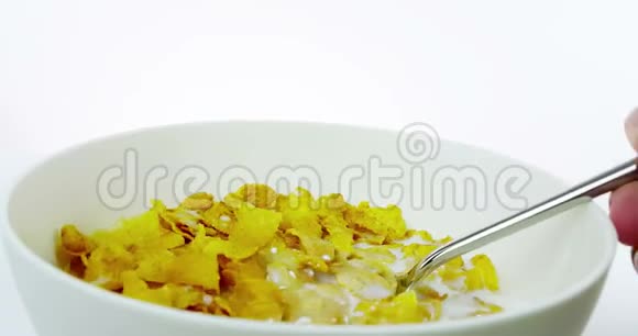 有人用勺子在碗里吃谷物玉米片碗里有白色背景的牛奶饮食健康的概念视频的预览图