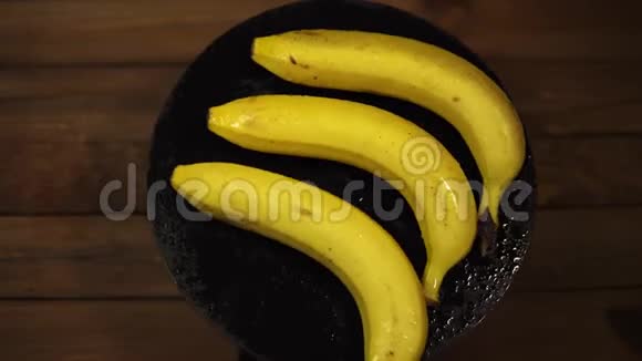 熟湿的香蕉在木桌上的黑色盘子上旋转视频的预览图