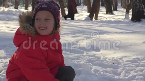 快乐的孩子在冬天的雪地里玩耍穿着暖和的衣服在冬天的公园里散步和玩耍的小女孩视频的预览图