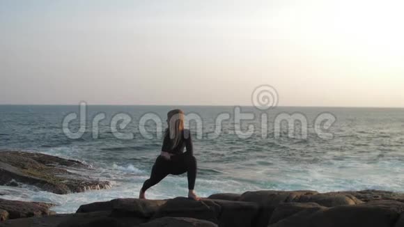 头发长长的年轻女子在灰色的岩石悬崖上伸展视频的预览图