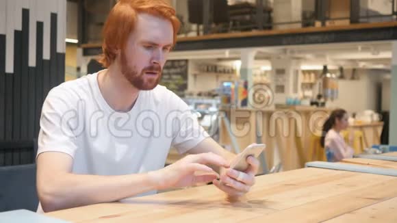 坐在咖啡馆的红头胡子男因失业而心烦意乱视频的预览图