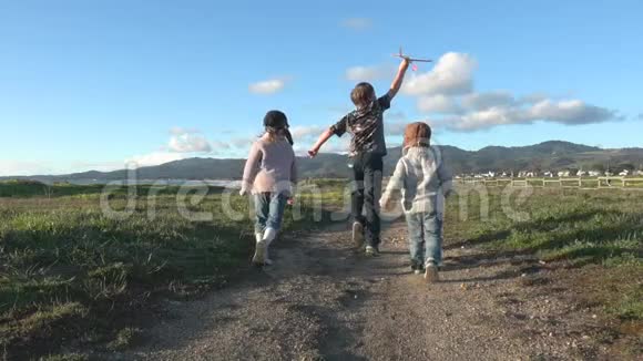 三个快乐的孩子在外面玩玩具飞机视频的预览图
