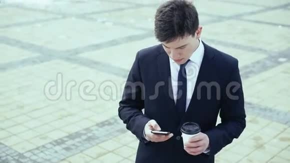 年轻的商人在户外喝咖啡写短信4k视频的预览图