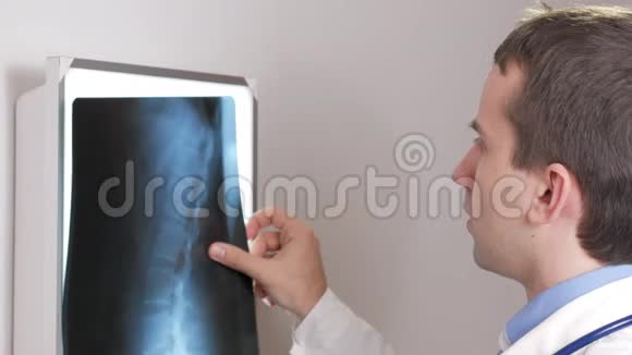 一位年轻的医生在墙上检查一位病人X光检查结果胸部和肋骨的分析视频的预览图