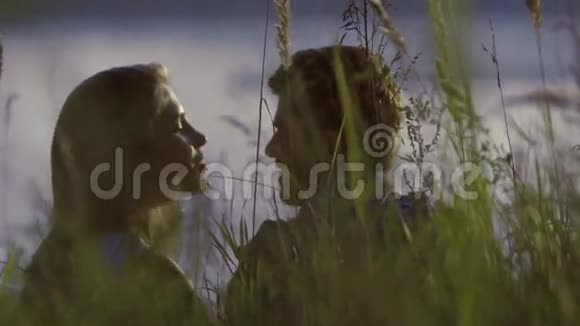 亲密的接吻情侣坐在高高的草地上视频的预览图