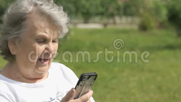 微笑的老妇人用智能手机说话视频的预览图