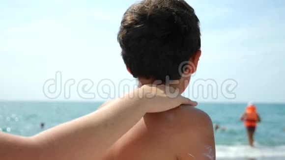 妈妈在海滩上给儿子涂防晒霜4k慢动作视频的预览图
