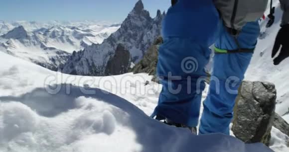 登山者在阳光明媚的日子里用冰斧在雪山顶附近攀登登山滑雪活动冬季滑雪者视频的预览图