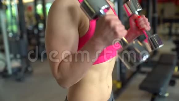 肌肉发达的女运动员穿着粉红色上衣在健身房锻炼举重健身女孩在健身房锻炼视频的预览图