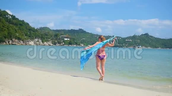 一个带着帕雷奥的年轻女孩在海滩的岸边热带小岛夏日的暖风视频的预览图
