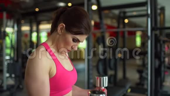 肌肉发达的女运动员穿着粉红色上衣在健身房锻炼举重健身女孩在健身房锻炼视频的预览图