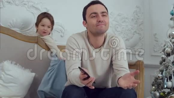 小男孩用枕头打他忙碌的父亲视频的预览图