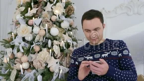 圣诞针织品快乐的年轻人通过手机发送信息视频的预览图