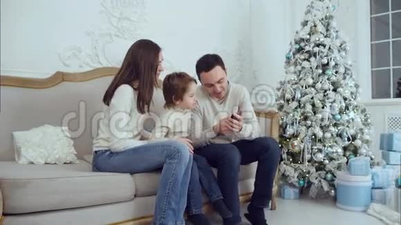年轻的幸福家庭在电话里看着他们的照片笑着视频的预览图