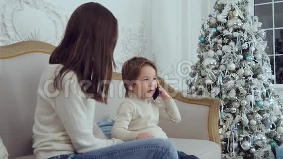 小男孩在电话里说他和妈妈一起坐在沙发上准备圣诞礼物视频的预览图