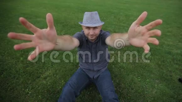 时尚年轻人戴着帽子坐在草地上摆姿势视频的预览图