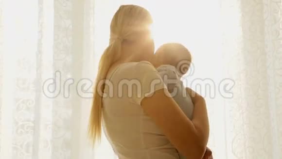 美丽快乐的妈妈妈妈和她的小男孩站在大窗户边看太阳视频的预览图