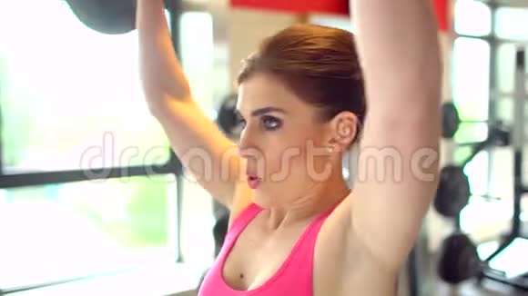 肌肉发达的女运动员穿着粉红色上衣在健身房锻炼举重健身女孩在健身房锻炼这就是视频的预览图
