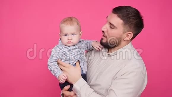 父亲带着可爱的小儿子粉红色的背景视频的预览图