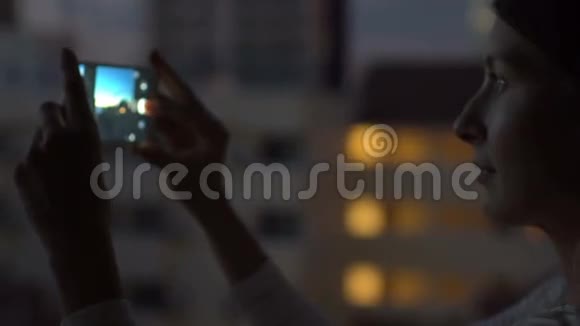 夜间在酒吧屋顶露台用智能手机拍摄城市景观的特写镜头视频的预览图