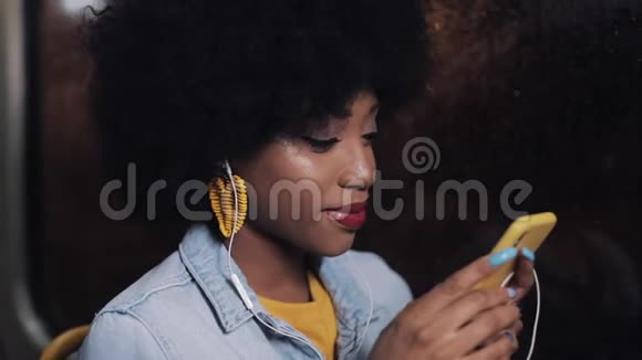 漂亮的非裔美国年轻女性在公共交通工具上使用智能手机晚上城市灯光背景视频的预览图