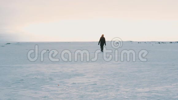 穿着黑色衣服在冰雪覆盖的平地上行走的人的剪影视频的预览图