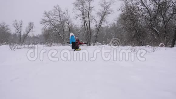 快乐的童年概念孩子和母亲在雪地里雪橇女儿和妈妈在圣诞节的冬季公园玩耍视频的预览图